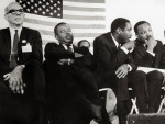 Dick Gregory talking Rev. Martin Luther King, Jr. on stage with Dr. Benjamin Spock, Rev. Ralph Abernathy (BETTMANN ARCHIVE).